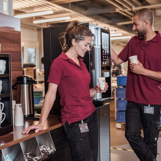 Zwei Mitarbeitende in der Fertigung genießen während einer kurzen Pause einen Kaffee aus der BARISTA Duro.