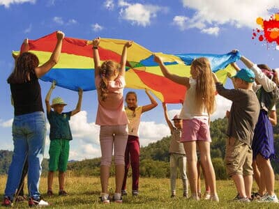 Kinder auf Wiese mit Regenbogentuch