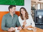 Mann-und-frau-mit-kaffee-am-tisch-vor-kaffeevollautomat