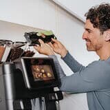 Person-füllt-kaffeebohnen-in-barista-ultima