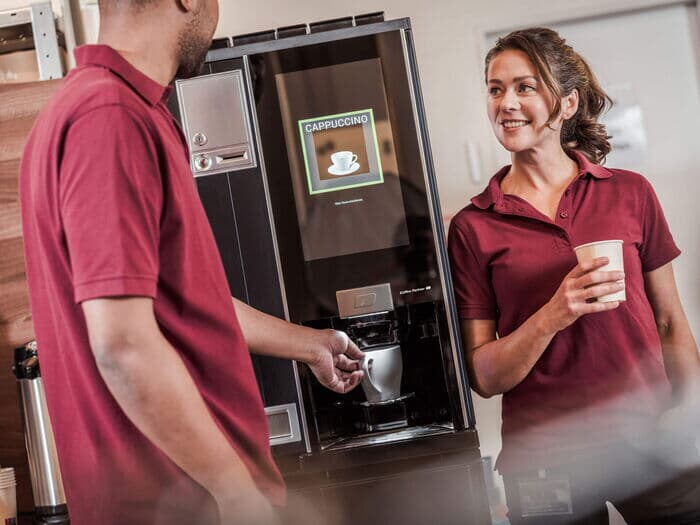 Cappuccino-wird-zubereitet-mitarbeiter-warten-am-kaffeeautomaten