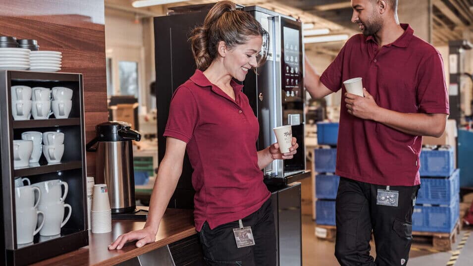 Zwei Mitarbeitende in der Fertigung genießen während einer kurzen Pause einen Kaffee aus der BARISTA Duro.